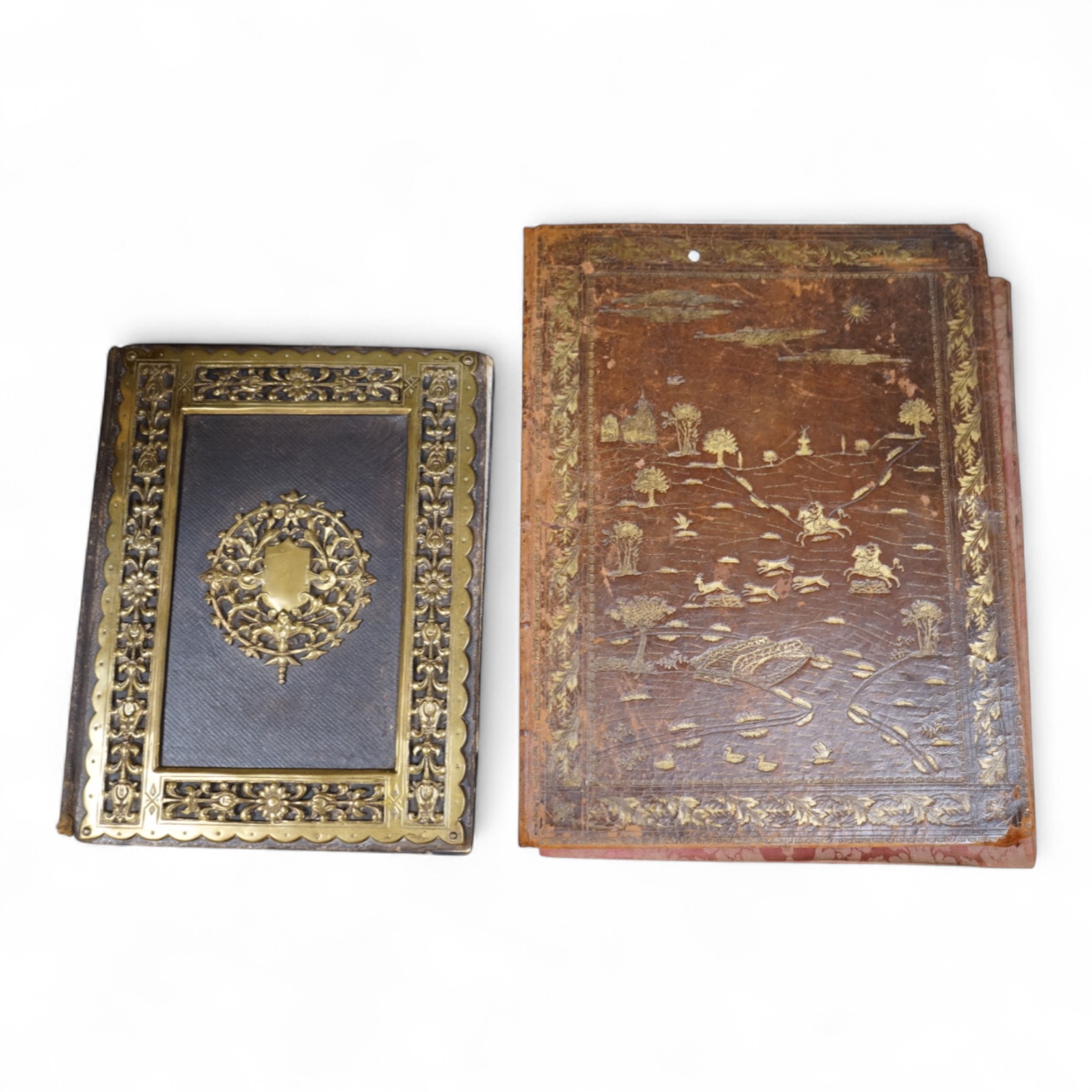 An ornate brass mounted and Morocco leather blotter and a tooled leather blotter of a Persian hunting scene with a red damask lining